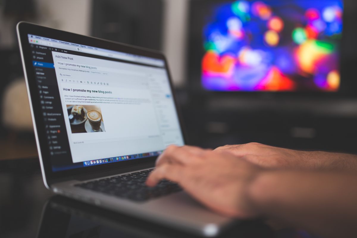 Tangan mengetik di laptop dengan tulisan blog terlihat di layar